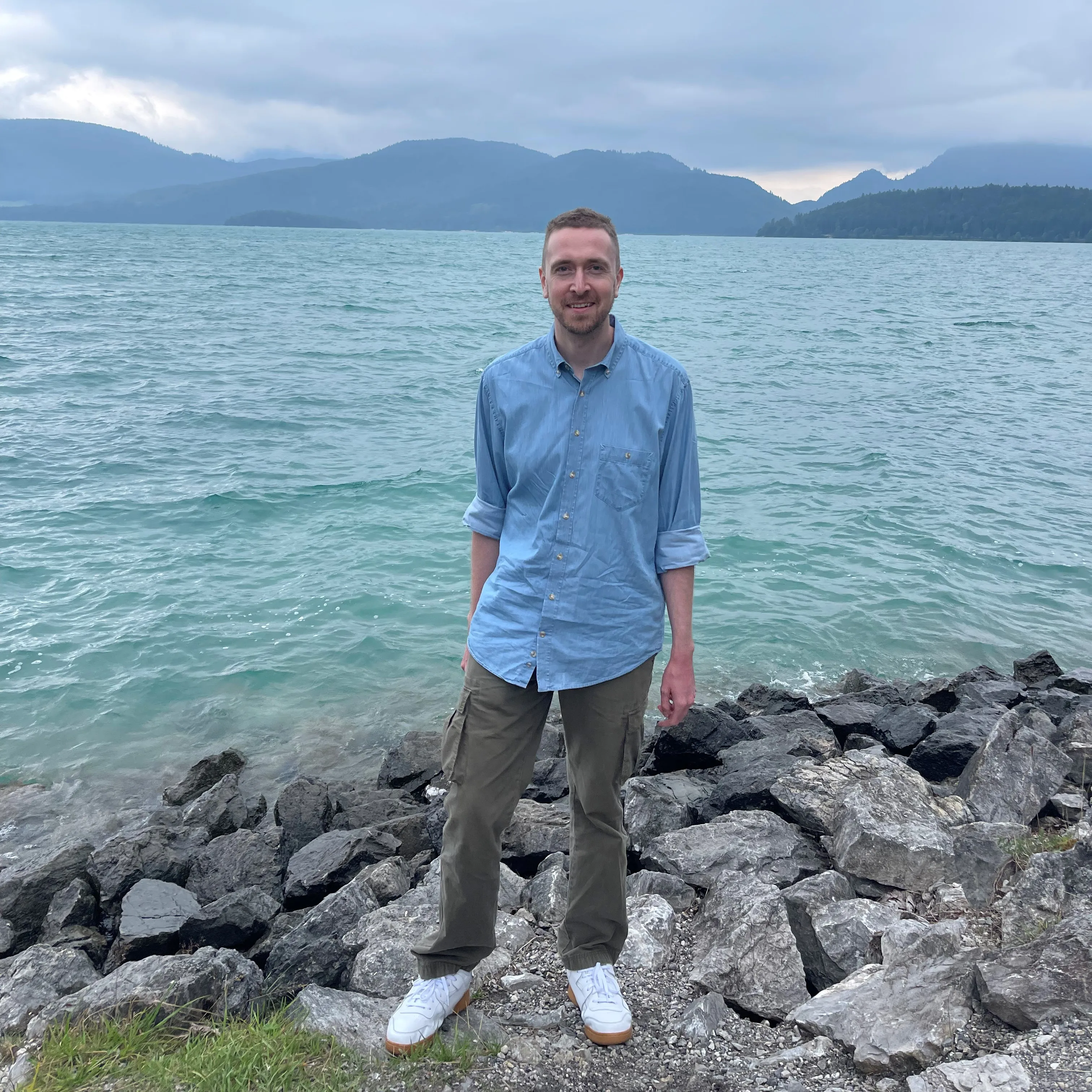 Tom, founder of Voyage, sitting on rocks by the coast